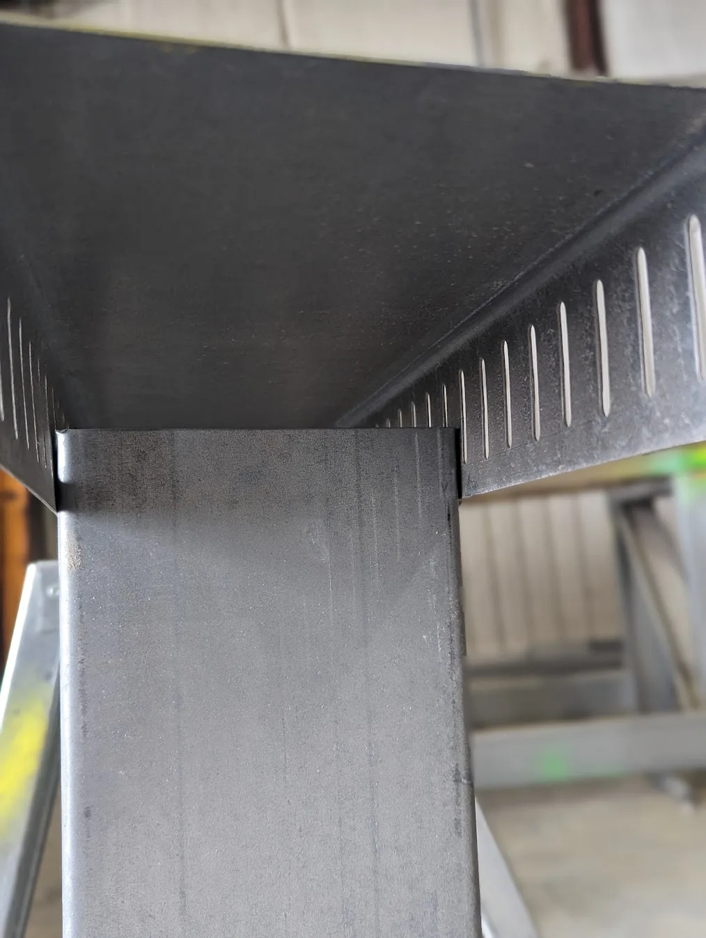 Close-up of a cold-formed steel stud seated in slotted deflection track roll formed on a Scottsdale KFS Framemaker 1220G3 steel framing roll former, with evenly spaced vertical slots punched inline along the track flanges, a FRAMECAD alternative for light-gauge steel framing