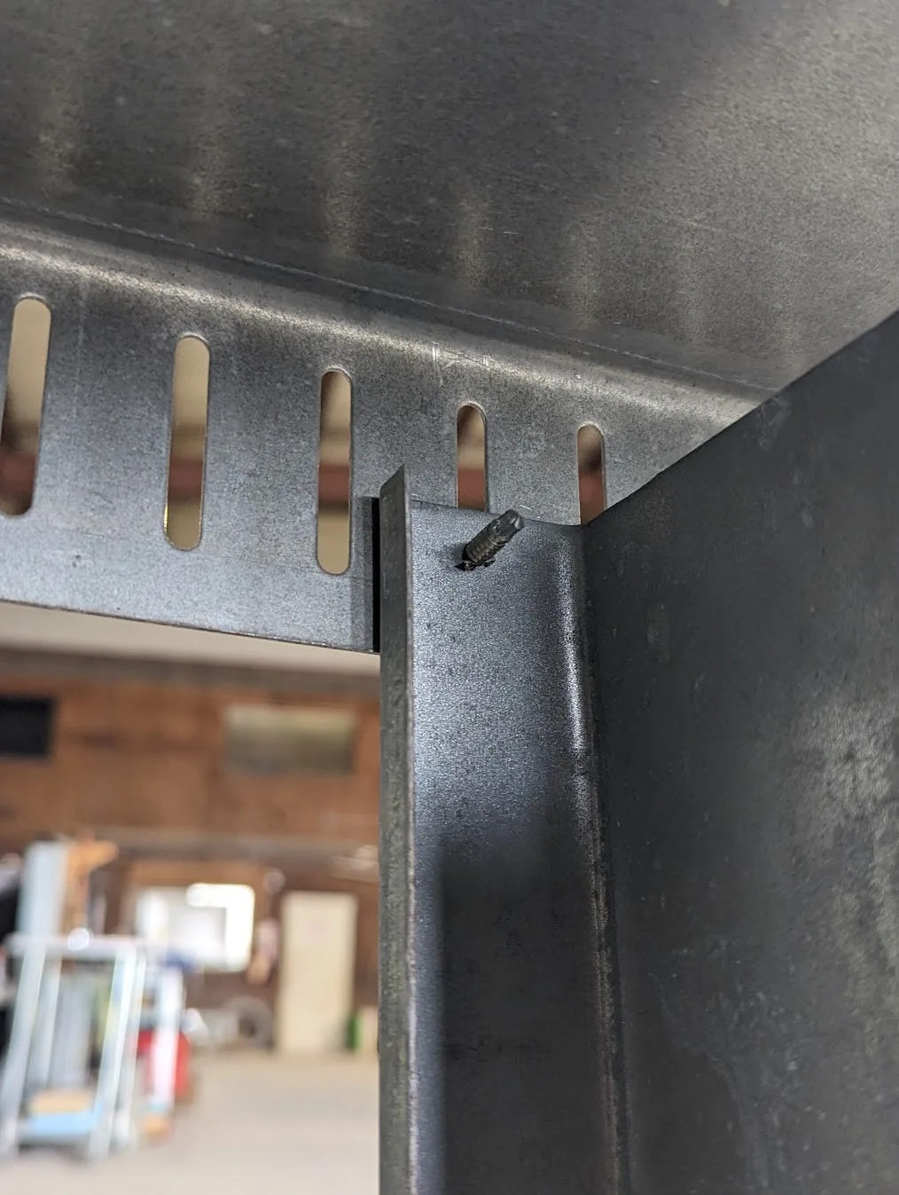 Light-gauge steel stud fastened to slotted deflection track with a self-drilling screw through a vertical slot, both members produced on the Scottsdale KFS Framemaker 1220G3 roll forming machine, an alternative to Howick steel framing machines